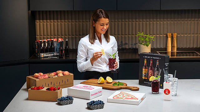 A woman in a kitchen with fresh produce and beverages.