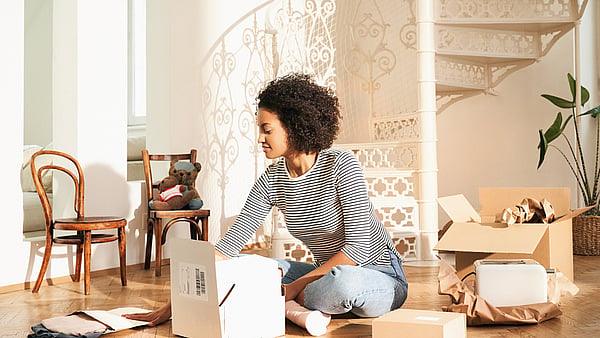 Lady wearing a black and white stripey top sitting cross legged on the floor surrounded by boxes and unpacking a Mondi MailerBag
