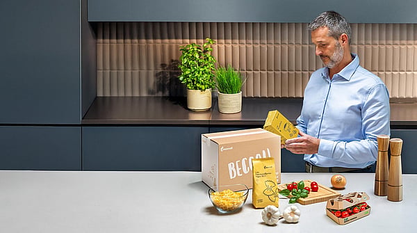 man standing at kitchen counter examining text on food packaging