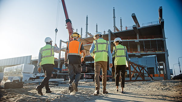 four workers on a construction site in wearing high-viz yellow and orange jackets