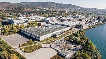 Aerial photograph of Mondi’s Duino mill near Trieste, Italy, surrounded by a river and mountains.