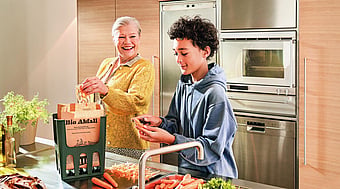 An older lady and a young boy in a kitchen preparing food whilst surrounded by Mondi's Advantage MF EcoComp packaging.
