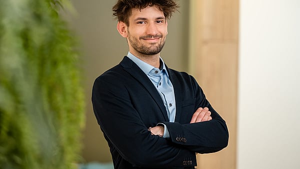man in shirt and blazer standing cross armed and smiling at the camera