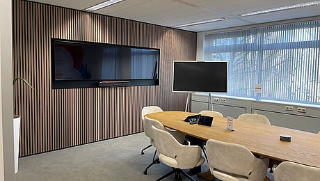 boardroom with long table and chairs around it facing a blank TV screen