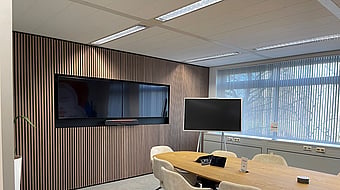 boardroom with long table and chairs around it facing a blank TV screen