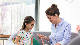 A woman and young girl sitting on a sofa unpackaging a product from a Mondi MailerBag
