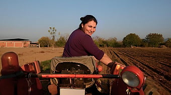 lady operating a tractor out in a field