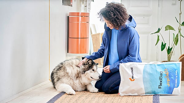 woman kneels down to pet a dog with packaging to her side