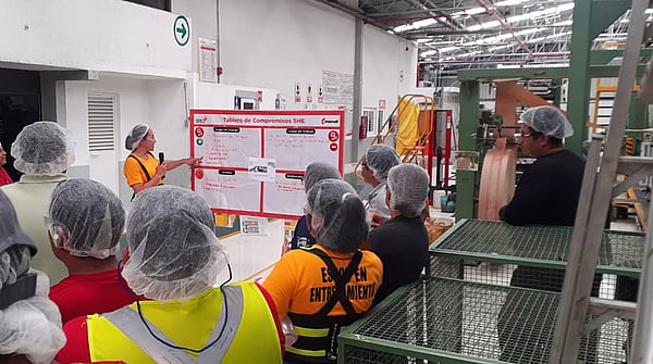 Mondi colleagues wearing safety equipment gathered around a whiteboard, listening to a colleague speaking.