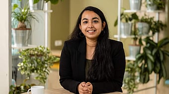 lady in black blazer facing the camera and smiling while sat down