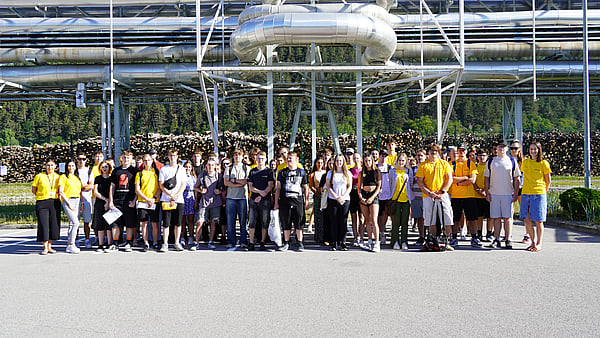 group of students pose for a photo outside a production site