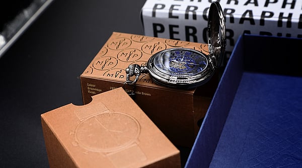 open pocketwatch sat on top of luxury Pergraphica packaging